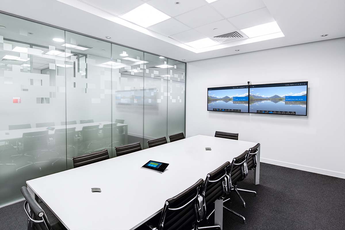 Ett vitt och ljust konferensrum med två tv-skärmar på väggen